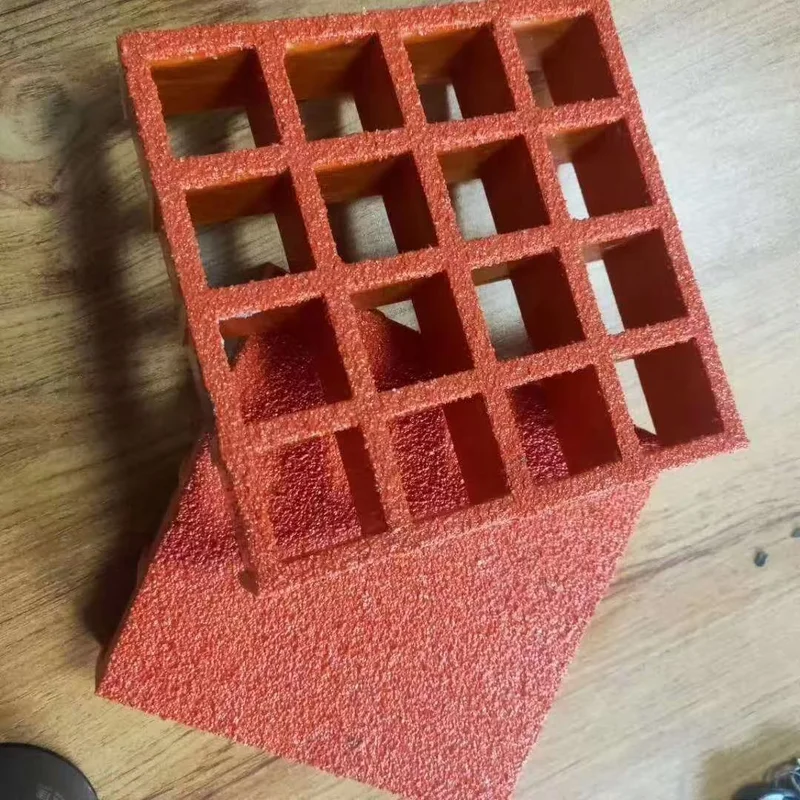 Red molded FRP grating sample showing square openings, bar depth and a textured surface