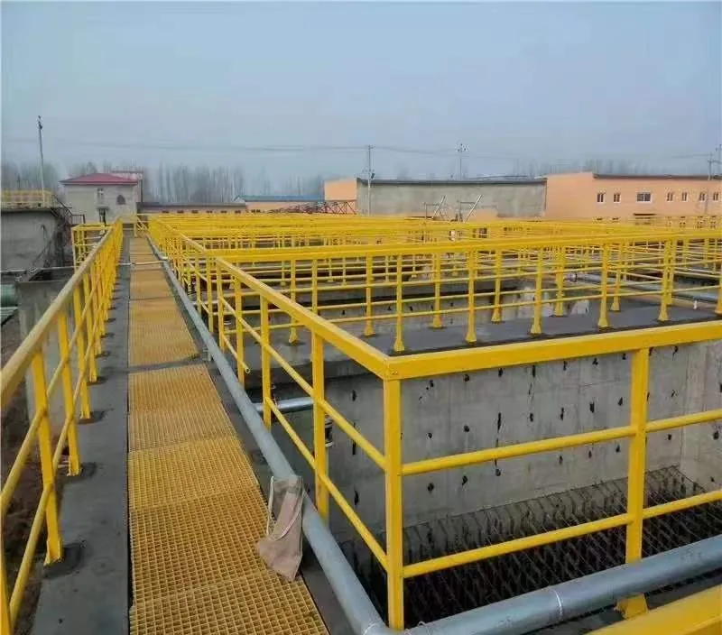 Yellow molded FRP grating walkway panels fixed to supports above a treatment tank, with a handrail alongside