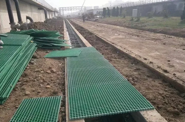 Green molded FRP grating panels laid over a culvert beside a construction road