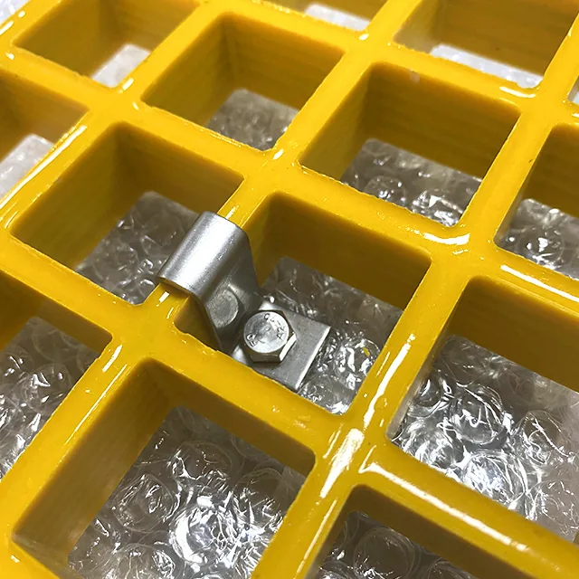 Metal L clip seated on a single bar of a yellow molded FRP grating panel with a bolt and nut beside it
