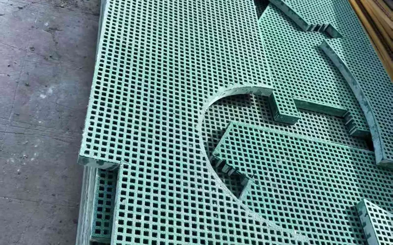 Factory-cut green FRP grating pieces with rectangular openings and treated edges