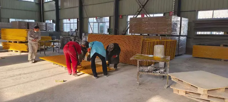 Workers finishing yellow FRP grating panels inside the factory