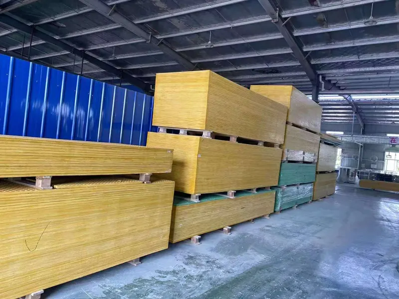 Stacks of yellow and green FRP grating panels on pallets in factory storage