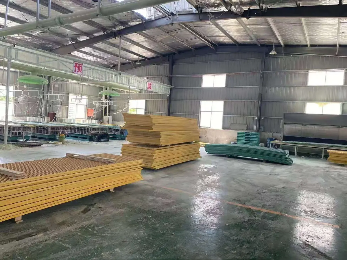 Factory workshop with grating molds and stacks of yellow and green FRP panels