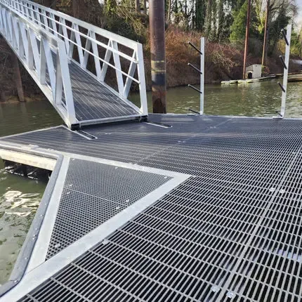 Open-mesh grating walkway on a floating dock beside water