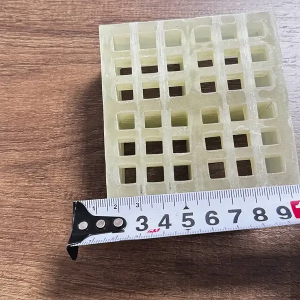 FRP grating sample beside a ruler as a visual size reference