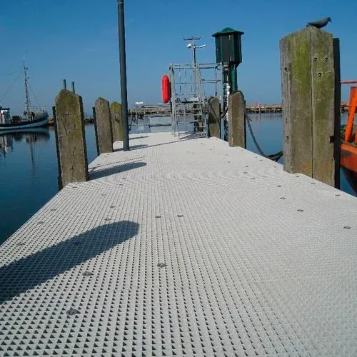 Open grating walkway with yellow rail beside a vessel and open water