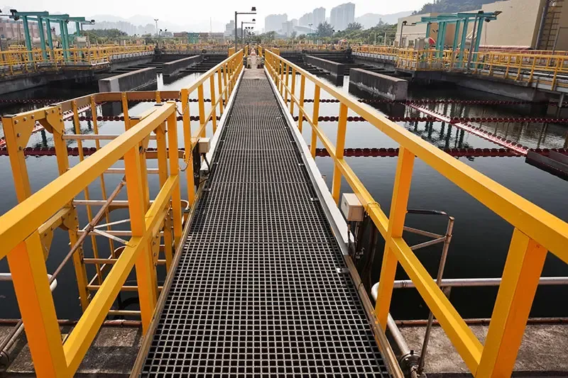 Grating walkway and handrails beside water-treatment tanks