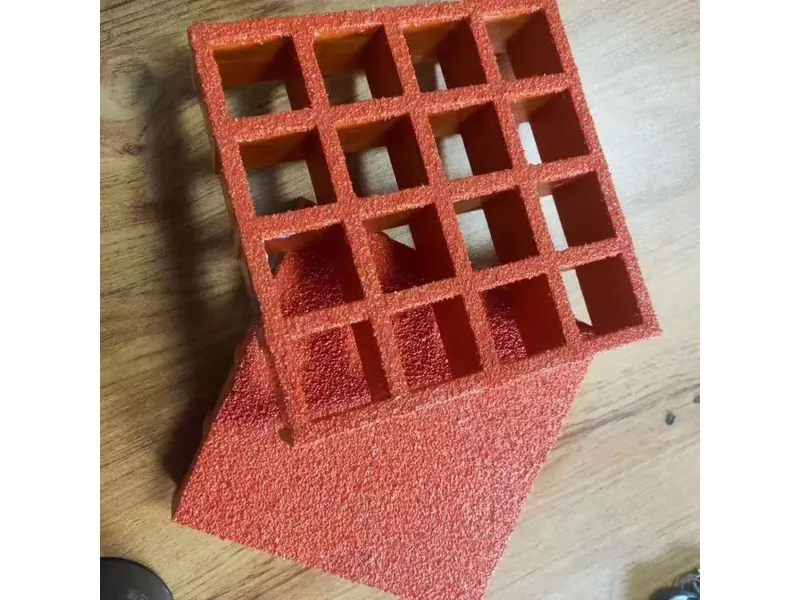 Red molded FRP grating sample with square openings and a textured surface