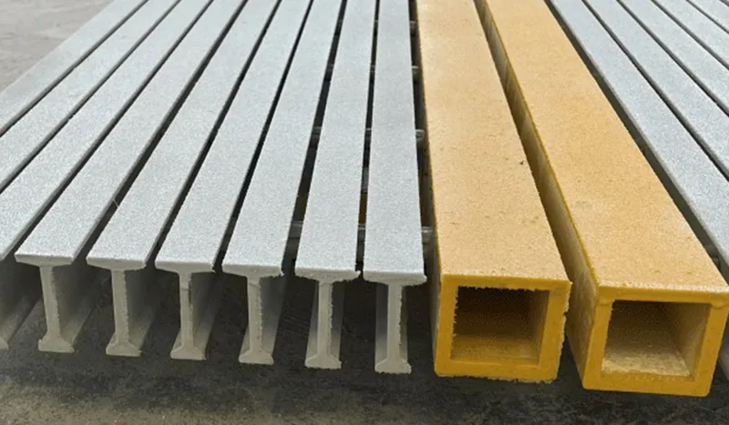 Cut ends of gray I-shaped pultruded bearing bars beside yellow hollow profiles